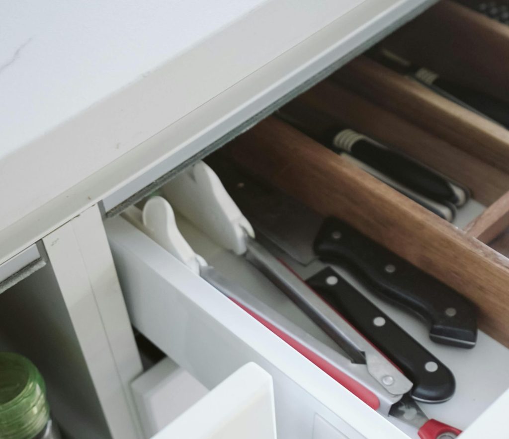 Neatly arranged kitchen drawer with knives and utensils, showcasing effective organization.