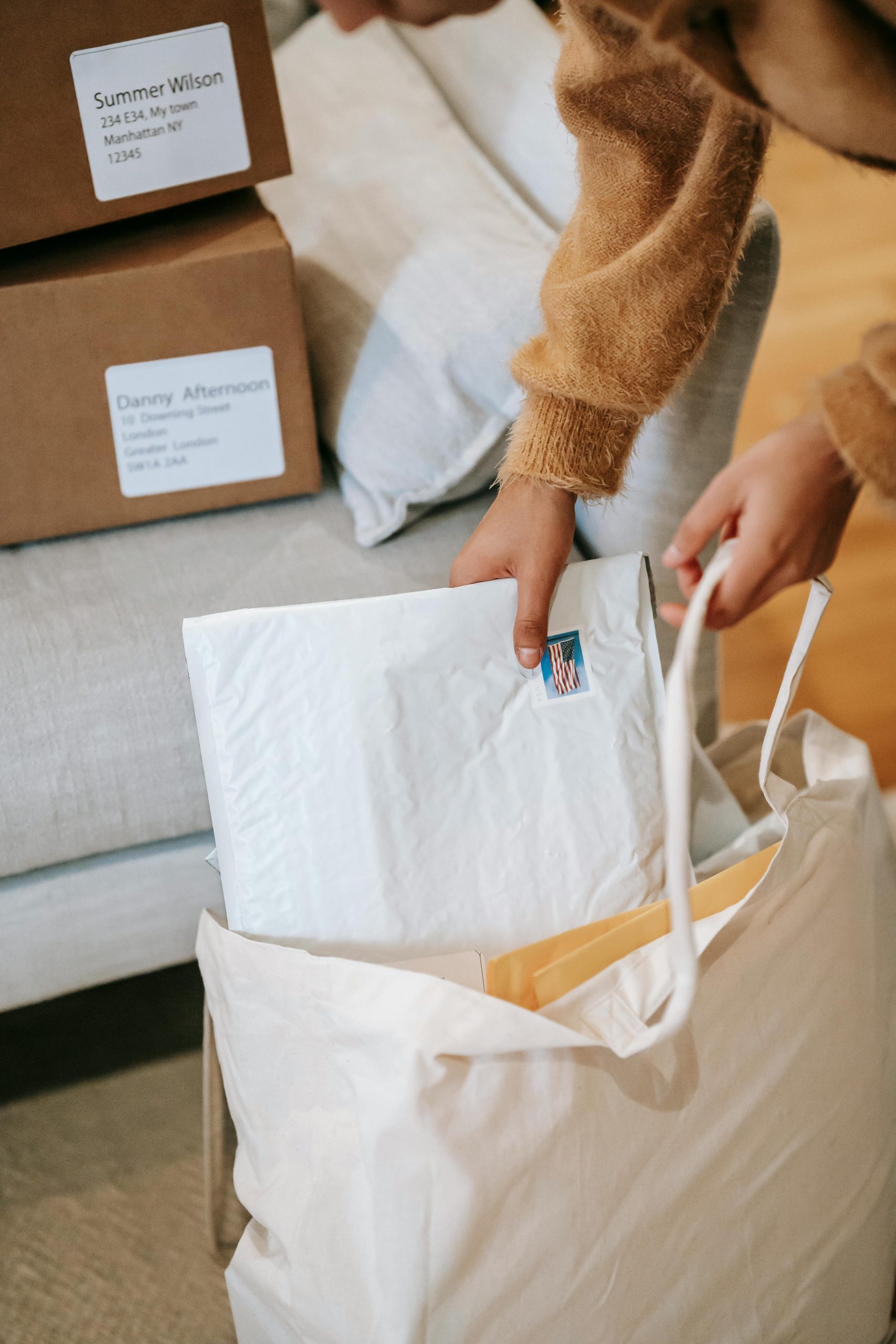 A person organizing padded envelopes and parcels at home, creating a warm and organized atmosphere.